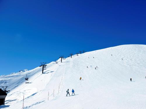 a group of people skiing down a snow covered ski slope at Hakuba Highland Hotel in Hakuba