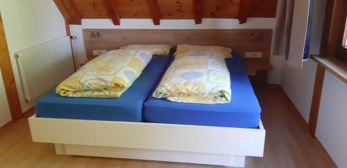 2 Betten in einem kleinen Zimmer mit blauer Bettwäsche und Kissen in der Unterkunft Martina Frey Ferienwohnungen in Baiersbronn