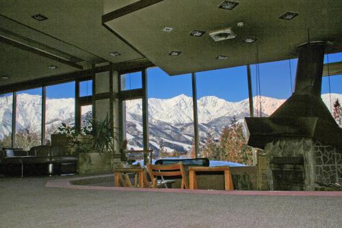 a living room with a fireplace and a view of mountains at Hakuba Highland Hotel in Hakuba