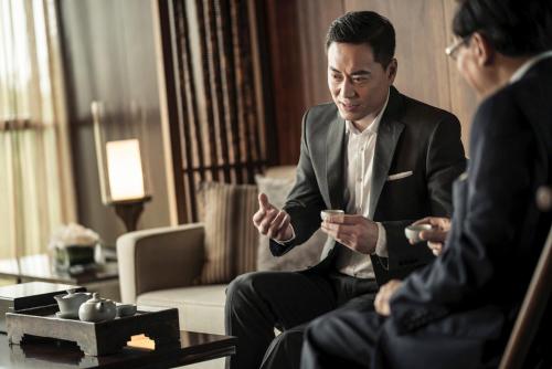 a man in a suit talking to two people in a room at HUALUXE Yangjiang City Center in Yangjiang
