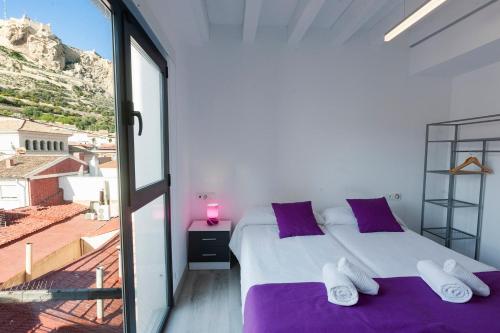 Un dormitorio con una cama con almohadas moradas y una ventana en Apartamentos Tito San Nicolas, en Alicante