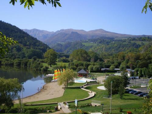 a park with a lake and mountains in the background at Logis Hôtel Le Beau Site in Chambon-sur-Lac