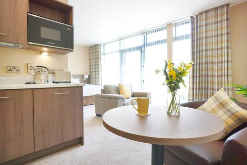 a living room with a kitchen and a table with flowers on it at Bannview Bed & Breakfast in Portadown