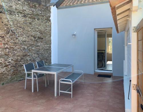 une table et des chaises sur une terrasse avec un mur en briques dans l'établissement Côté Source, à Pornic