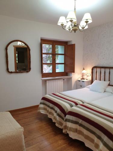 a bedroom with a bed and a mirror and a window at Casa Rural La Pumarada de Limés in Cangas del Narcea