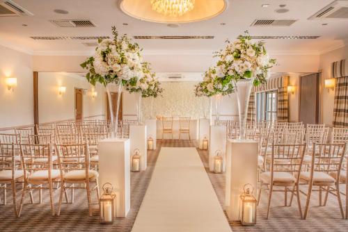 a wedding hall with chairs and tables and flowers at voco Oxford Thames by IHG in Oxford