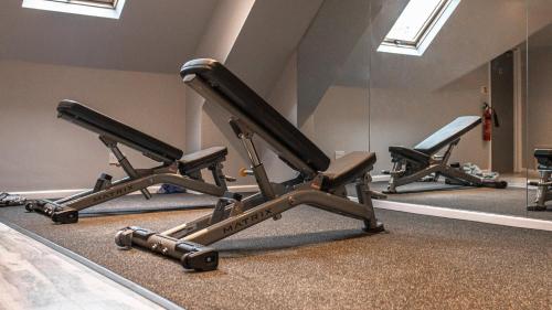 a row of exercise equipment in a room with a mirror at voco Oxford Thames by IHG in Oxford