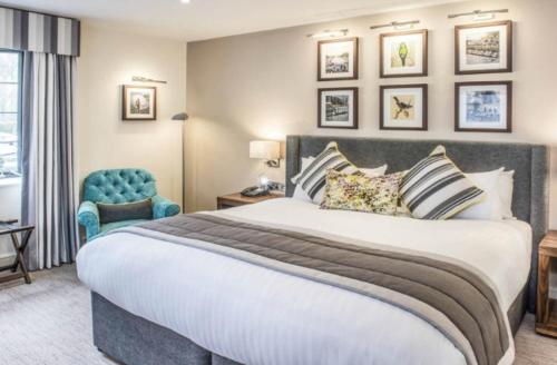 a bedroom with a large bed and a blue chair at voco Oxford Thames by IHG in Oxford