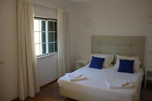 um quarto com uma cama com almofadas azuis e uma janela em Villa V2 C em Albufeira