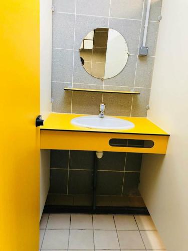 La salle de bains est pourvue d'un lavabo jaune et d'un miroir. dans l'établissement Camping Du Lion, à Bourg-Saint-Andéol