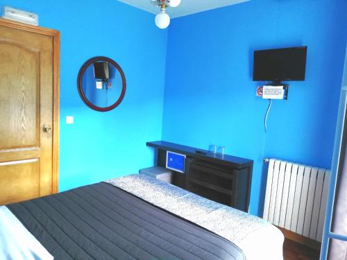 a blue bedroom with a bed and a television at Txoko Maitea Pentsioa in Urnieta