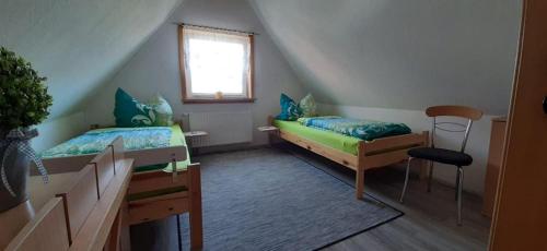 a attic room with two beds and a window at Ferienwohnung Aue in Bad Lauterberg