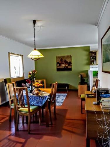 a dining room with a table and chairs and a green wall at Páteo memória, casa do beco in Setúbal