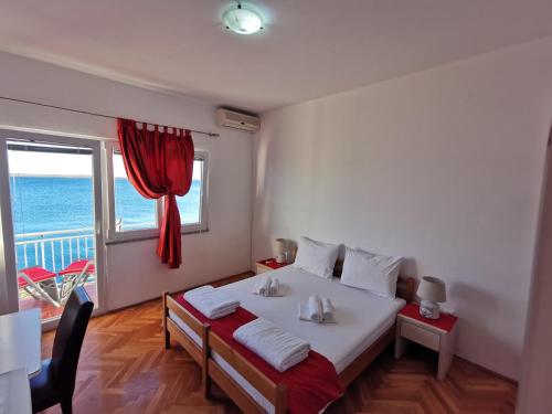 a bedroom with a bed and a window with the ocean at Rooms Ante in Tribanj-Krušćica