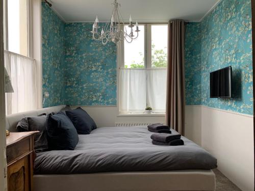 a bedroom with a bed with blue walls and a chandelier at B&B 't Raethuys in Dirkshorn