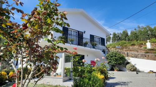 a white house with black windows and a balcony at Casa de Vilarinho in Arouca