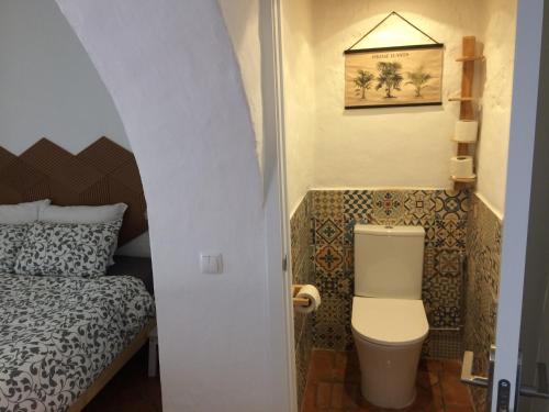 ein kleines Bad mit WC und ein Bett in der Unterkunft Quinta da Fornalha - Santuario Agroecologico in Castro Marim