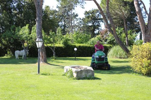 a woman driving a lawn mower in a park at Podere San Paolo in San Giuliano Terme