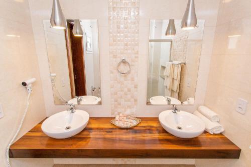 a bathroom with two sinks and two mirrors at LENA ROSA Premium Hotel in Pomerode