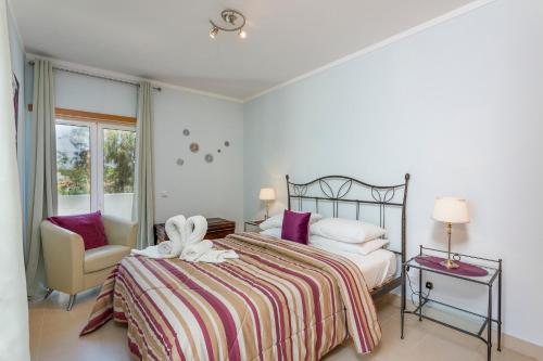 a bedroom with a bed and a chair and a window at Cabanas Beach Penthouse in Cabanas de Tavira