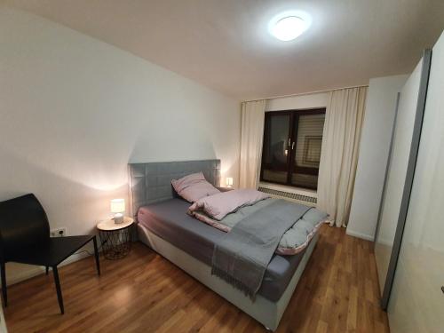 a bedroom with a bed and a chair and a window at 2-Zimmer-Apartment Ratingen Ost in Ratingen