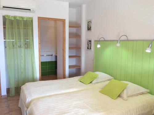 a bedroom with a large white bed with green walls at Le Mas des Eglantiers in Propiac