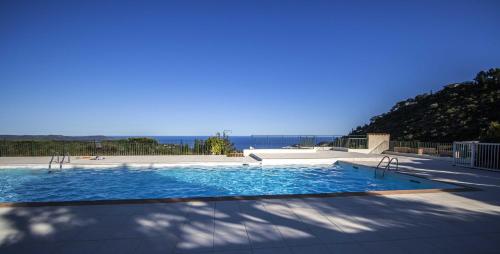 une grande piscine avec l'océan en arrière-plan dans l'établissement Villa Les Albizias, à Cavalaire-sur-Mer