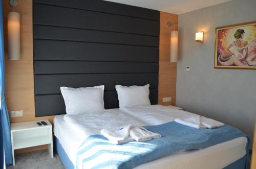 a bedroom with a bed with two white shoes on it at MOBI DICK Family Hotel in Glavatartsi