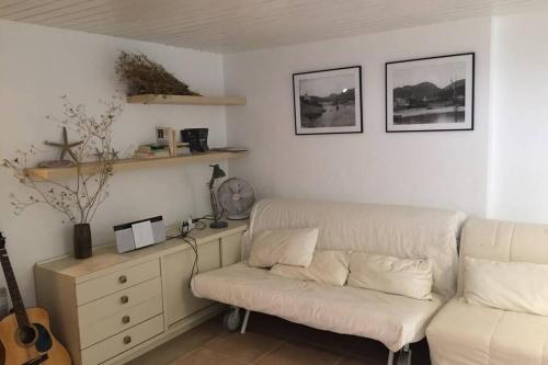 - un salon avec un canapé blanc et une guitare dans l'établissement LA CASSIRENE - Maisonnette centre Cassis - Jardin, à Cassis