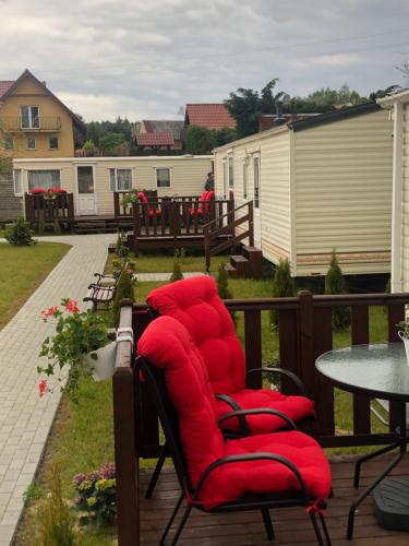 a row of red chairs sitting on a deck at MIĘDZY NAMI domki nad jeziorem in Kołczewo