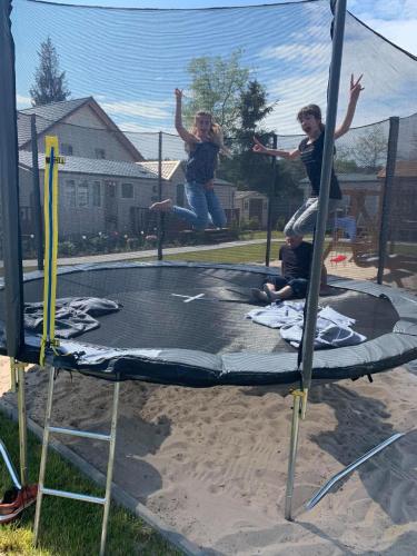 two women jumping on top of a trampoline at MIĘDZY NAMI domki nad jeziorem in Kołczewo