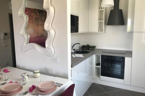 a white kitchen with a table and a mirror at Luna27 in Toscolano Maderno
