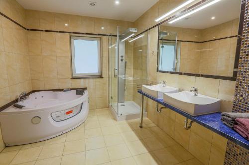 łazienka z 2 umywalkami, wanną i prysznicem w obiekcie LouisaPark w Łagowie