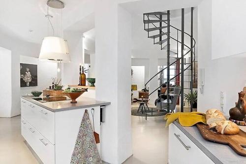 a white kitchen with a spiral staircase in a room at Ystads Gamla Vattentorn in Ystad