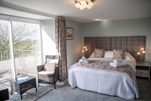 a bedroom with a bed and a large window at Tregaddra Farm B&B in Helston