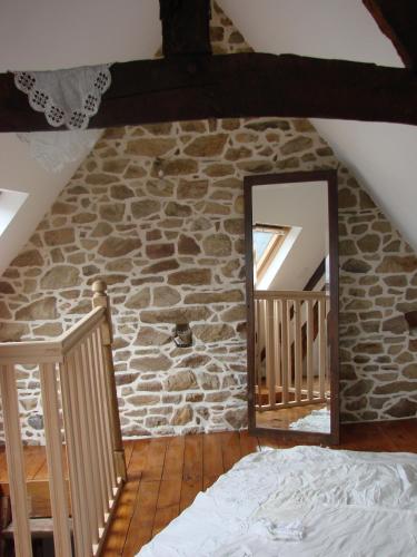 - une chambre avec un miroir et un mur en pierre dans l'établissement CHAMBRE ROMANTIQUE CHEZ L'HABITANT à LAMBALLE, à Lamballe