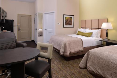 a hotel room with two beds and a table at Candlewood Suites Morgantown-Univ West Virginia by IHG in Morgantown
