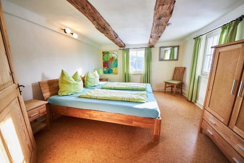 Schlafzimmer mit einem Bett mit blauer Bettwäsche und gelben Kissen in der Unterkunft Hof Bergidyll in Bürberg