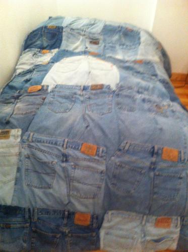 a bed covered in blue jeans with orange tags at CHAMBRE JEAN'S CHEZ L'HABITANT à LAMBALLE in Lamballe