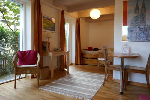 ein Wohnzimmer mit einem Tisch, Stühlen und einem Fenster in der Unterkunft Öko-Ferienwohnung-Kiel im Schwedenhaus in Kiel