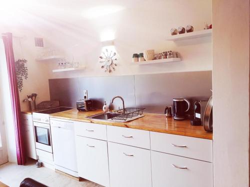 a kitchen with white cabinets and a sink at Bastide Provençale Les Mûriers d'Engaspaty in Seillans