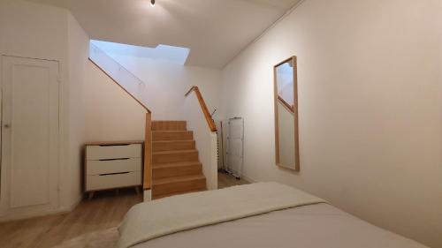 ein Schlafzimmer mit einer Treppe und einem Bett mit einem Spiegel in der Unterkunft Joli T2- centre ville - Parking gratuit - WIFI in Dunkerque
