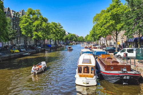 a group of boats are docked in a canal at Hotel Alexander in Amsterdam