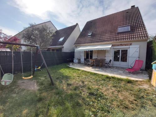 einen Hinterhof mit einer Schaukel und einem Haus in der Unterkunft Disneyland/Paris 1 a10 personnes climatisee in Pontault-Combault