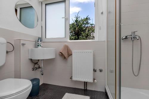 a bathroom with a toilet and a shower and a window at Apartments & Rooms Rica in Makarska
