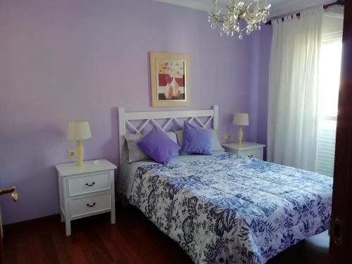 um quarto com paredes roxas e uma cama com almofadas roxas em Apartamento en Duplex em Jerez de la Frontera
