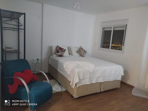 a bedroom with a bed and a chair and a window at Terraço Harmony Flats GRU in Guarulhos