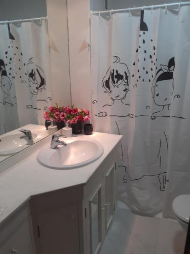 a bathroom with a sink and a shower curtain with flowers at Apartamento Nuit in Teruel