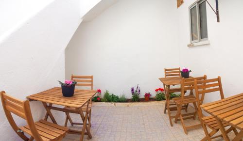 een patio met houten tafels, stoelen en bloemen bij Alagoa Terrace Guesthouse in Faro