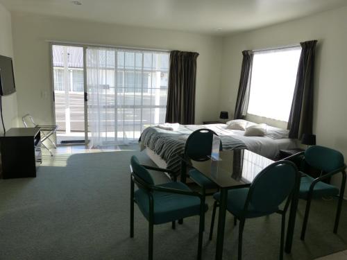 1 dormitorio con 1 cama, mesa y sillas en Blake Court Motel, en Whangamata